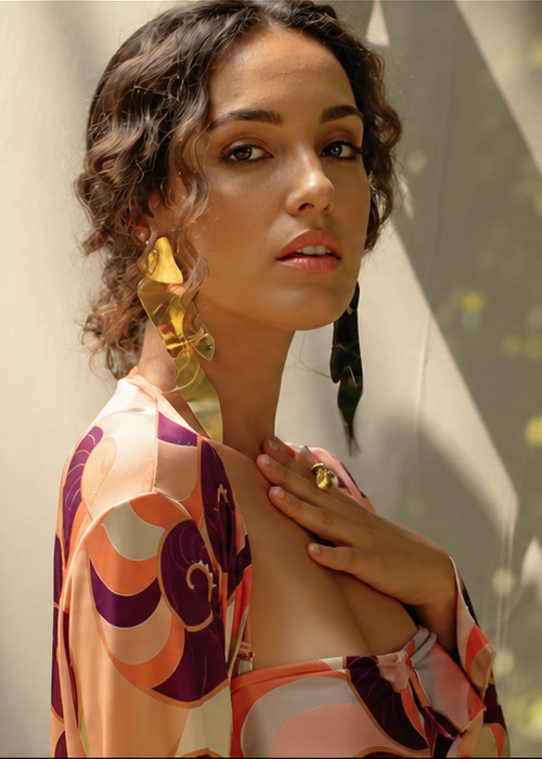 Bruna Pazinato em quadro de clipe, vestido estampado e luz de sol